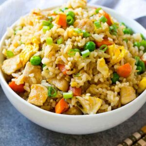 chicken "not-so" fried rice plated in a bowl on a concrete-like surface with chopsticks and a napkin.