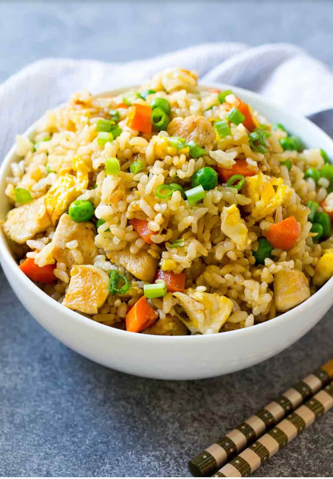 chicken "not-so" fried rice plated in a bowl on a concrete-like surface with chopsticks and a napkin.