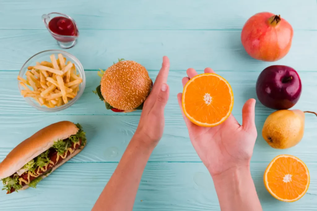 unhealthy and healthy food compared - burger, fries, hotdog vs assorted fruit